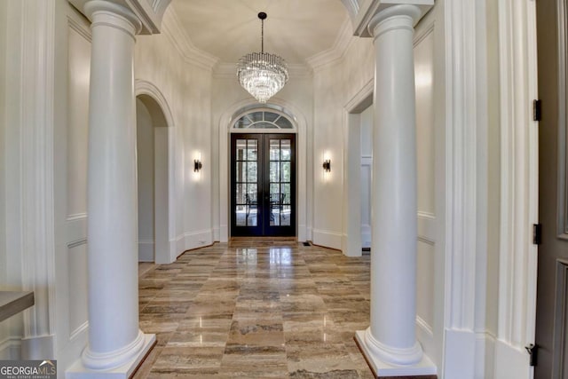 entrance foyer featuring crown molding, french doors, ornate columns, and arched walkways