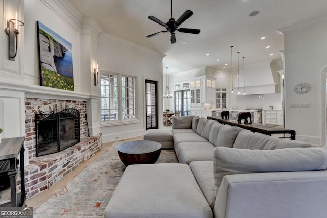living area featuring a wealth of natural light, a fireplace, ornamental molding, and ceiling fan