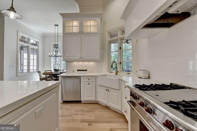 kitchen with an inviting chandelier, light wood-style floors, stainless steel appliances, a sink, and hanging light fixtures