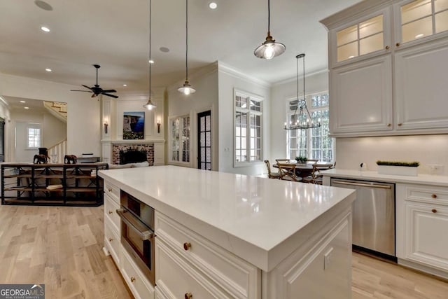 kitchen with light wood-style flooring, recessed lighting, appliances with stainless steel finishes, a brick fireplace, and open floor plan