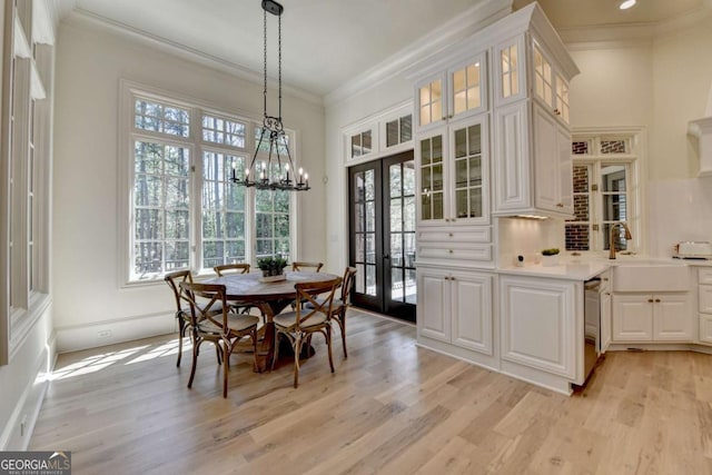 dining room with crown molding, plenty of natural light, and light wood-style floors