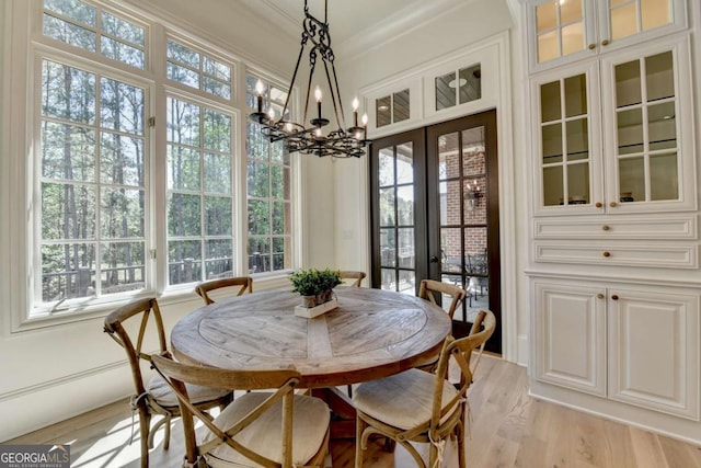 dining area featuring light wood-style floors, plenty of natural light, french doors, and a chandelier