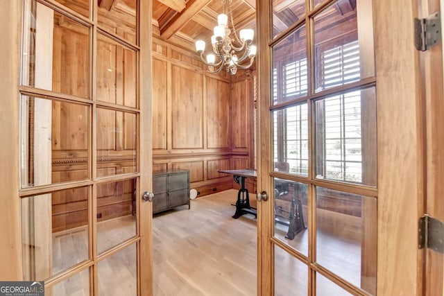 interior space with wooden ceiling, a notable chandelier, wooden walls, beam ceiling, and coffered ceiling