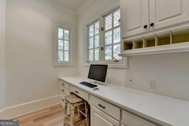 office featuring light wood-style flooring, ornamental molding, built in study area, and baseboards