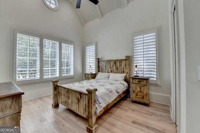 bedroom with light wood-style floors, beamed ceiling, and multiple windows