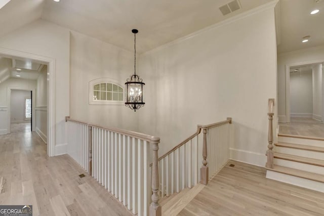 stairs with visible vents, attic access, vaulted ceiling, and wood finished floors