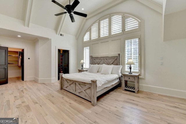bedroom with light wood-type flooring, high vaulted ceiling, multiple windows, and a walk in closet