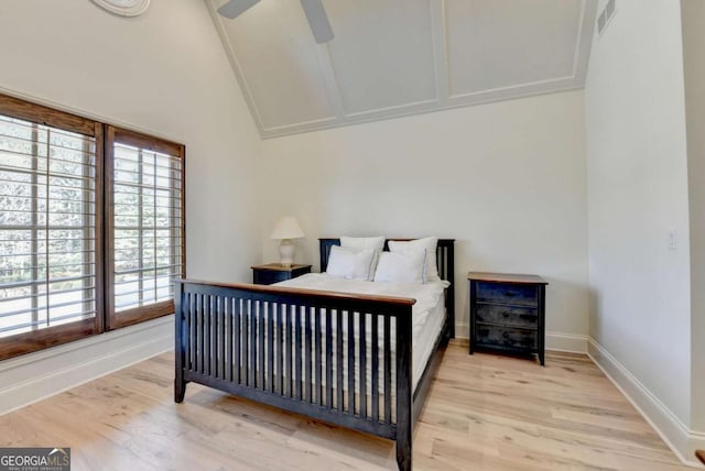 bedroom with baseboards, light wood-style floors, visible vents, and vaulted ceiling
