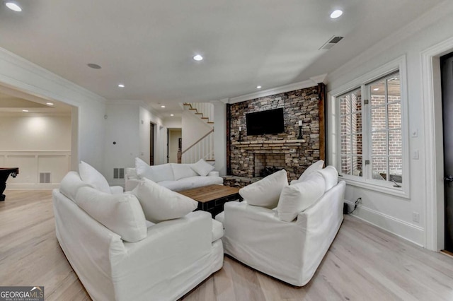 living room with crown molding, light wood finished floors, visible vents, and stairway