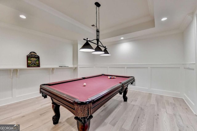 recreation room featuring a decorative wall, ornamental molding, and wood finished floors