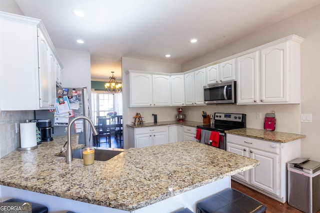 kitchen featuring a sink, white cabinetry, a peninsula, and stainless steel appliances