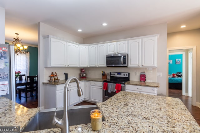 kitchen featuring dark wood finished floors, white cabinetry, a chandelier, and stainless steel appliances