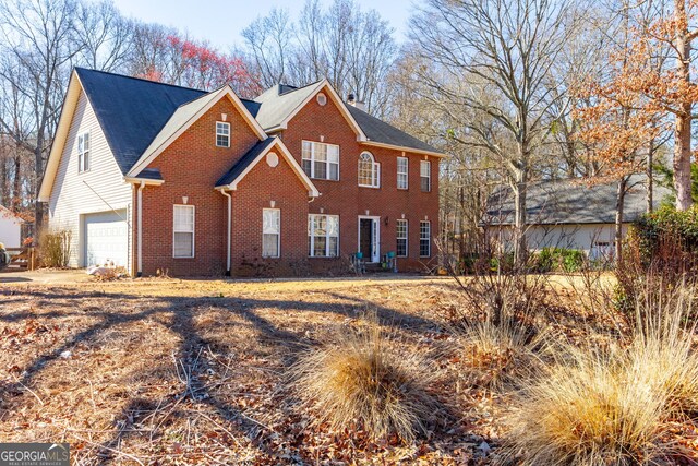colonial inspired home featuring a garage and brick siding