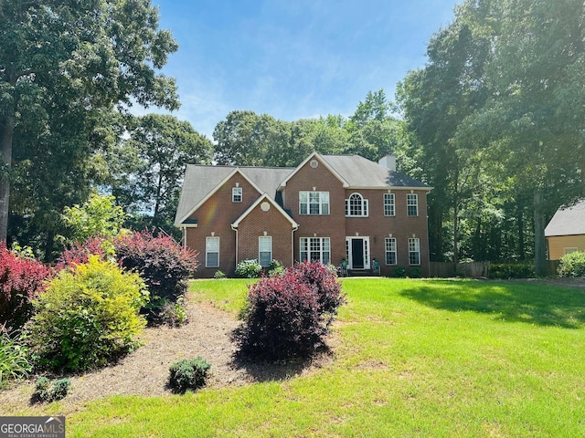 1036 Regency Park Dr, Braselton, GA 30517 - colonial house featuring brick siding, a front lawn, and a chimney