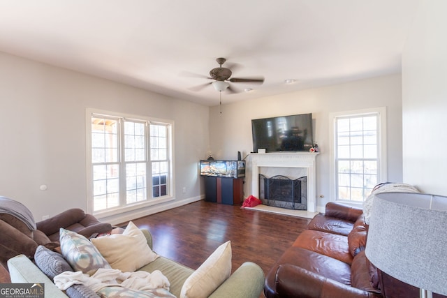 living area featuring wood finished floors, a fireplace, a ceiling fan, and baseboards