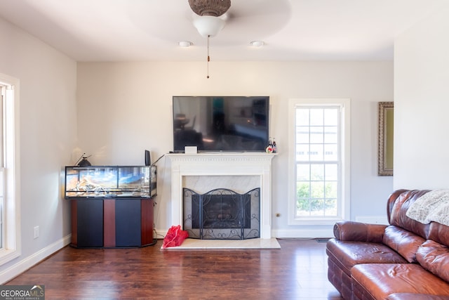 living room featuring a premium fireplace, baseboards, a ceiling fan, and wood finished floors