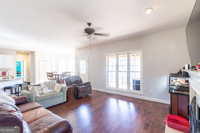 living area with visible vents, baseboards, a ceiling fan, and dark wood-style floors