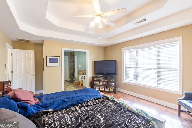 bedroom with visible vents, multiple windows, and a tray ceiling