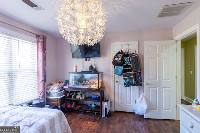 bedroom featuring visible vents, a chandelier, and wood finished floors