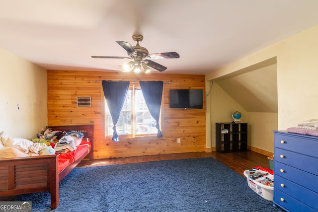 bedroom featuring wood walls, ceiling fan, wood finished floors, and lofted ceiling