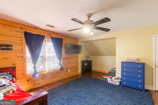bedroom featuring wood finished floors, wooden walls, lofted ceiling, and visible vents