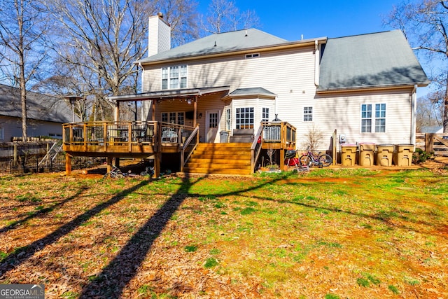 rear view of property with a yard, fence, a deck, and a chimney