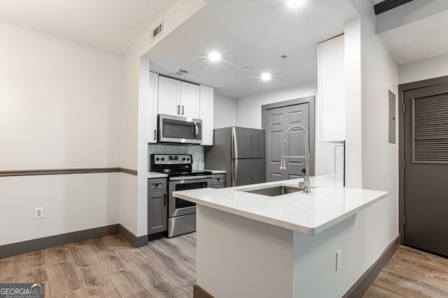 1074 Peachtree Walk NE Unit 115, Atlanta, GA 30309 - kitchen with stainless steel appliances, light stone counters, a peninsula, light wood-type flooring, and tasteful backsplash
