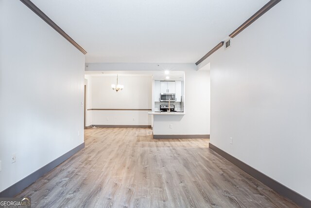 1074 Peachtree Walk NE Unit 115, Atlanta, GA 30309 - unfurnished living room with a chandelier, light wood finished floors, and ornamental molding