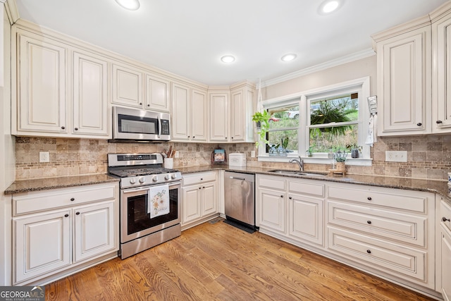 524 Allison Ln, Ball Ground, GA 30107 - kitchen with stainless steel appliances, ornamental molding, backsplash, dark stone countertops, and light wood-style flooring