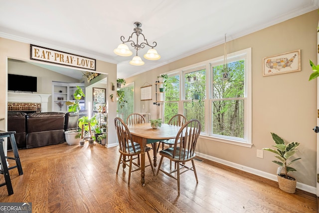 524 Allison Ln, Ball Ground, GA 30107 - dining area with crown molding, wood finished floors, a fireplace, and a chandelier