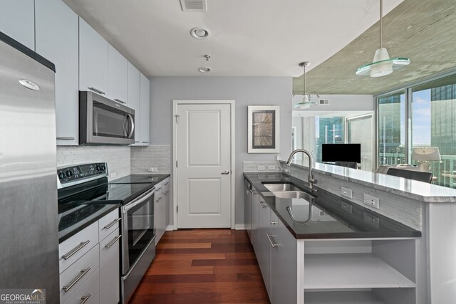 3324 Peachtree Rd NE Unit 1518, Atlanta, GA 30326 - kitchen featuring dark wood finished floors, a peninsula, appliances with stainless steel finishes, a sink, and backsplash