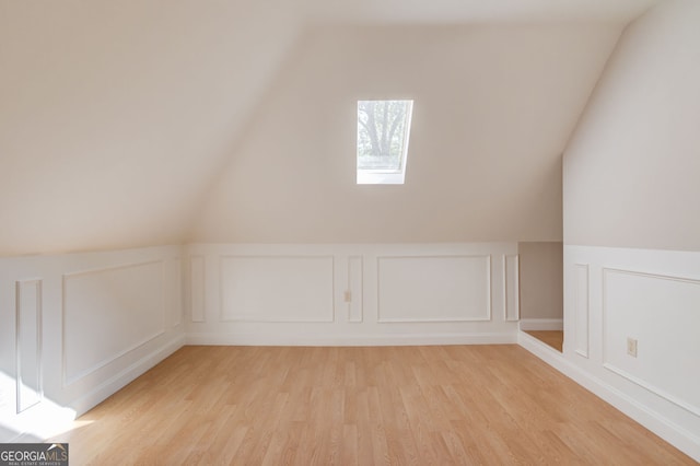 476 Walnut Rd, Hoschton, GA 30548 - bonus room with a decorative wall, light wood-style floors, vaulted ceiling, a skylight, and wainscoting