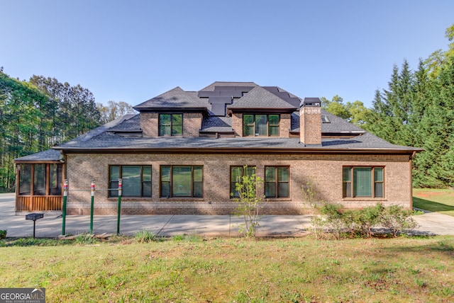 476 Walnut Rd, Hoschton, GA 30548 - back of property with a sunroom, a chimney, a yard, brick siding, and roof with shingles