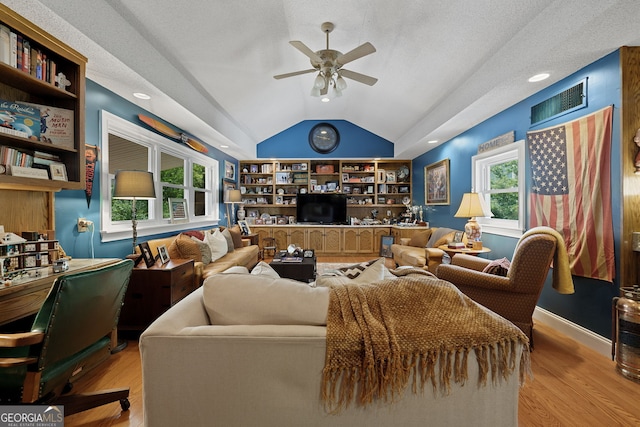 living area with visible vents, built in features, ceiling fan, light wood-type flooring, and lofted ceiling