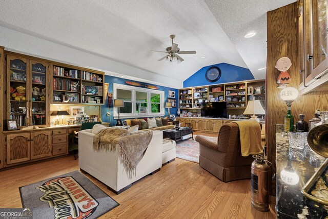 living room featuring light wood finished floors, ceiling fan, a textured ceiling, and lofted ceiling