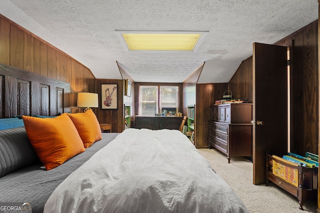 bedroom with light carpet, wooden walls, and a textured ceiling