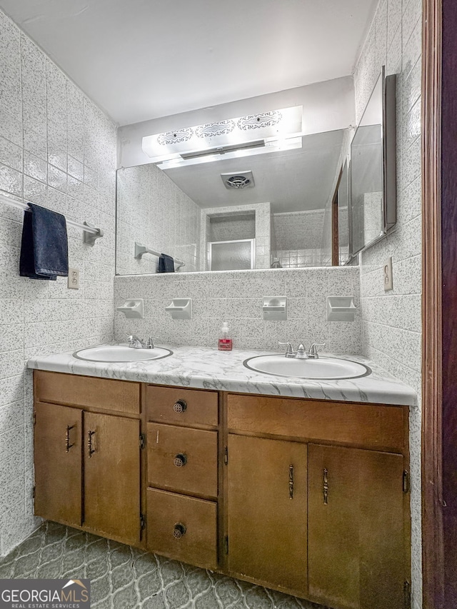 bathroom featuring visible vents, tile walls, a sink, and decorative backsplash