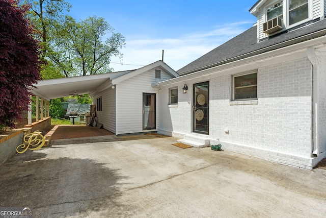 view of front of home with entry steps, a shingled roof, brick siding, concrete driveway, and an attached carport