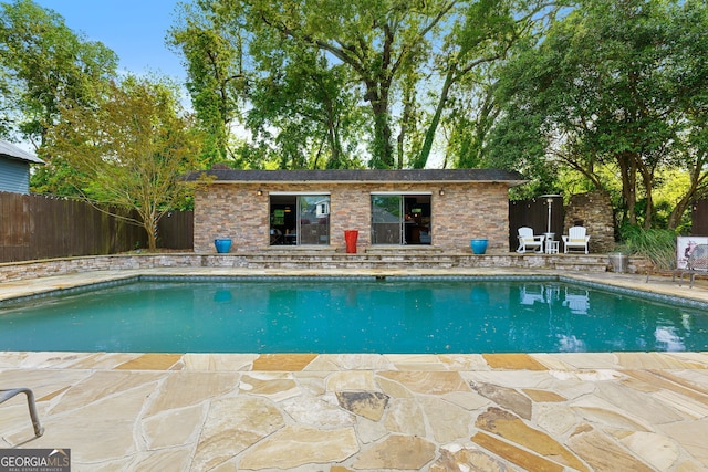 view of swimming pool with an outbuilding, a patio area, a fenced in pool, and fence