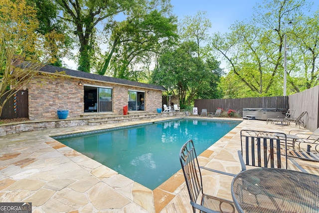 view of pool featuring a hot tub, a fenced backyard, an outdoor structure, a patio, and a fenced in pool