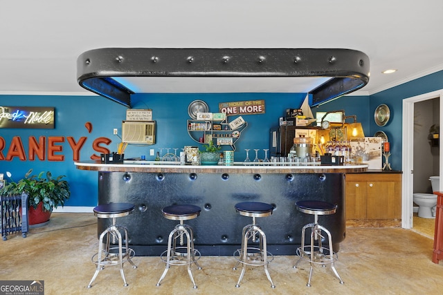 bar with finished concrete flooring, ornamental molding, and a community bar