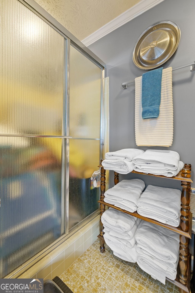 bathroom featuring tile patterned floors, ornamental molding, and a shower with door