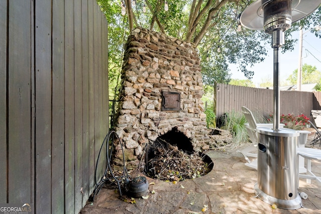 view of patio with a fireplace and fence