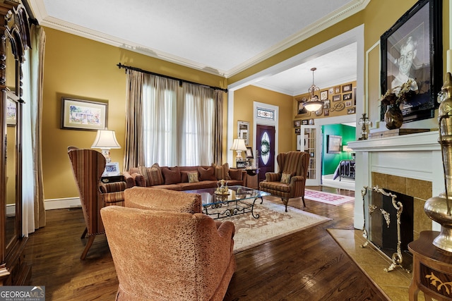 living area with dark wood finished floors, a tiled fireplace, crown molding, and a healthy amount of sunlight