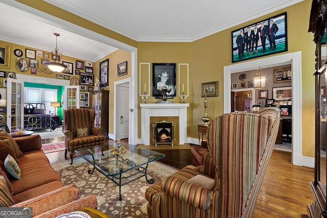 living area with a fireplace, baseboards, ornamental molding, and wood finished floors