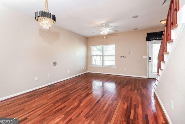 interior space featuring visible vents, ceiling fan with notable chandelier, baseboards, and dark wood finished floors