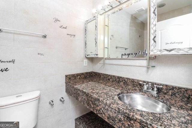bathroom with a sink, visible vents, tile walls, and toilet