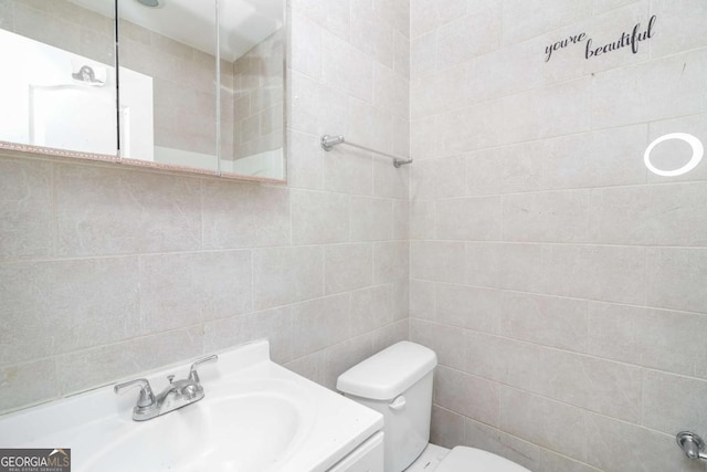 bathroom featuring vanity, tile walls, and toilet