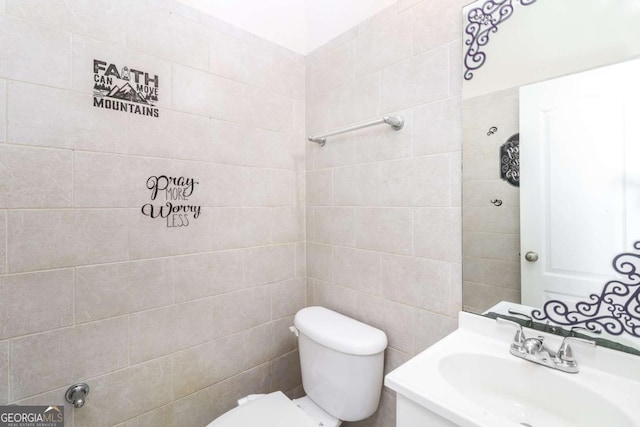 half bathroom with vanity, tile walls, and toilet
