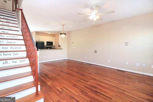unfurnished living room featuring visible vents, baseboards, ceiling fan, wood finished floors, and stairs